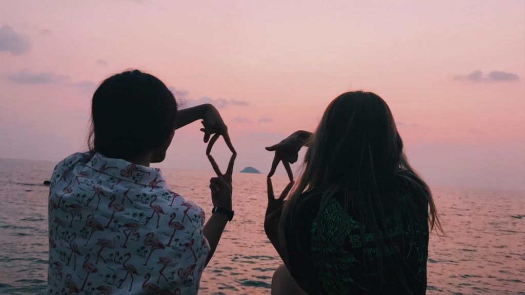 A couple (friends) sitting in front of a body of water