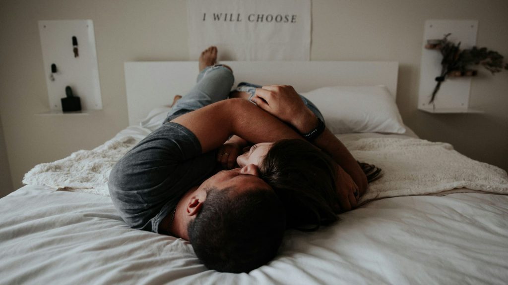 couple hugging each-other on white bed being happy and intimate