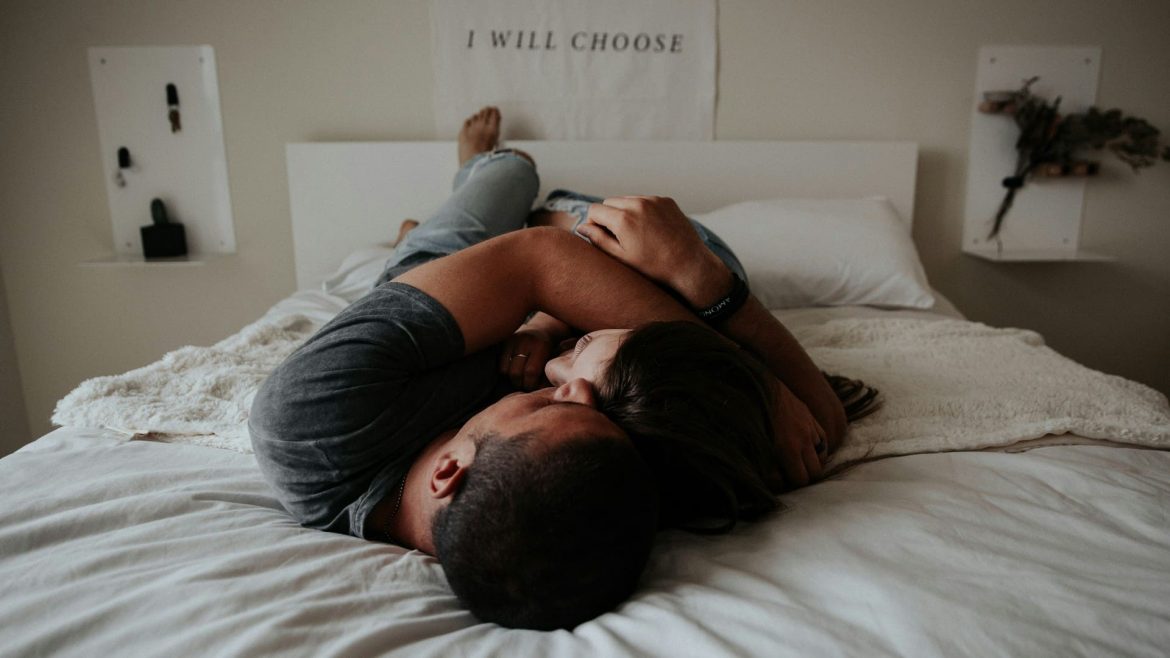 couple snuggling with each-other on white bed being happy and intimate